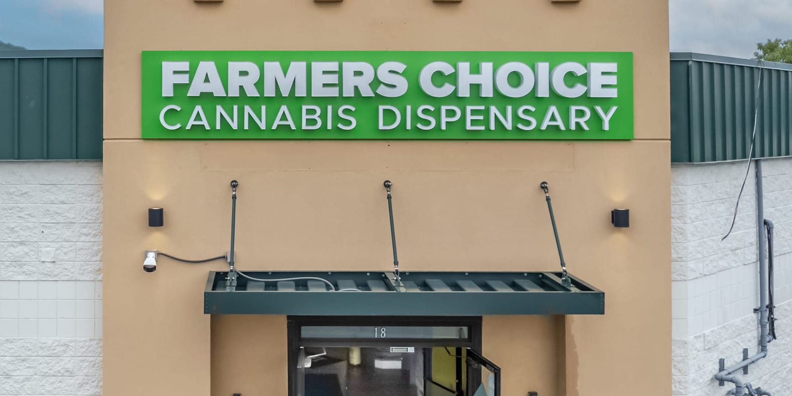 The green Farmers Choice Cannabis Dispensary sign over the entrance of the Fishkill store at 18 Westage Drive, a dark awning and glass doors below