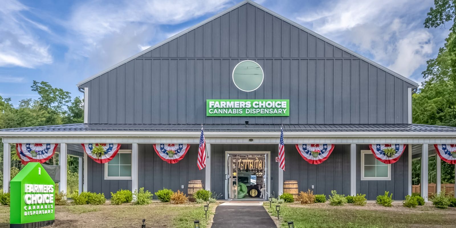 The Farmers Choice New Paltz barn seen head on, its wraparound porch hung with bunting and flags and whiskey barrels flanking the open entrance