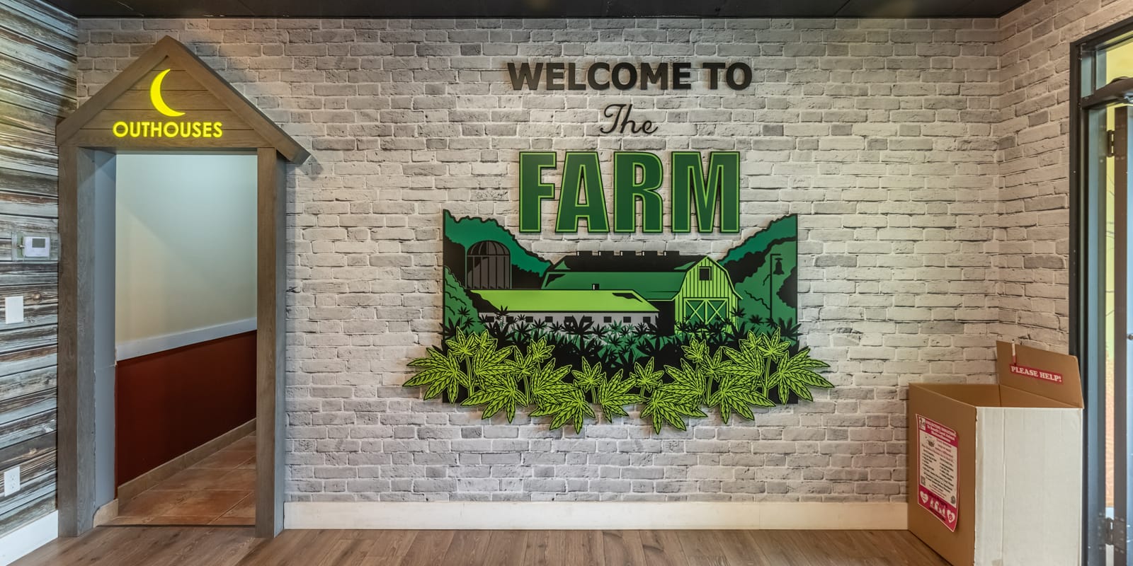The Welcome to the Farm mural at Farmers Choice Fishkill, a green barn and hills on white brick beside a doorway under a little outhouse sign