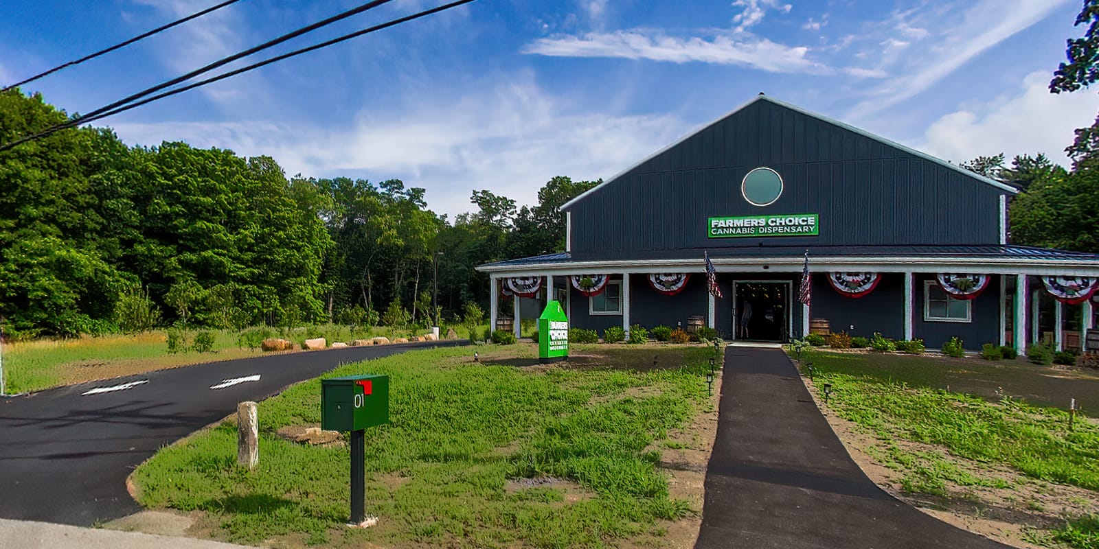 Farmers Choice New Paltz seen from the road, the gray barn and its green sign at the end of a long walkway across the lawn