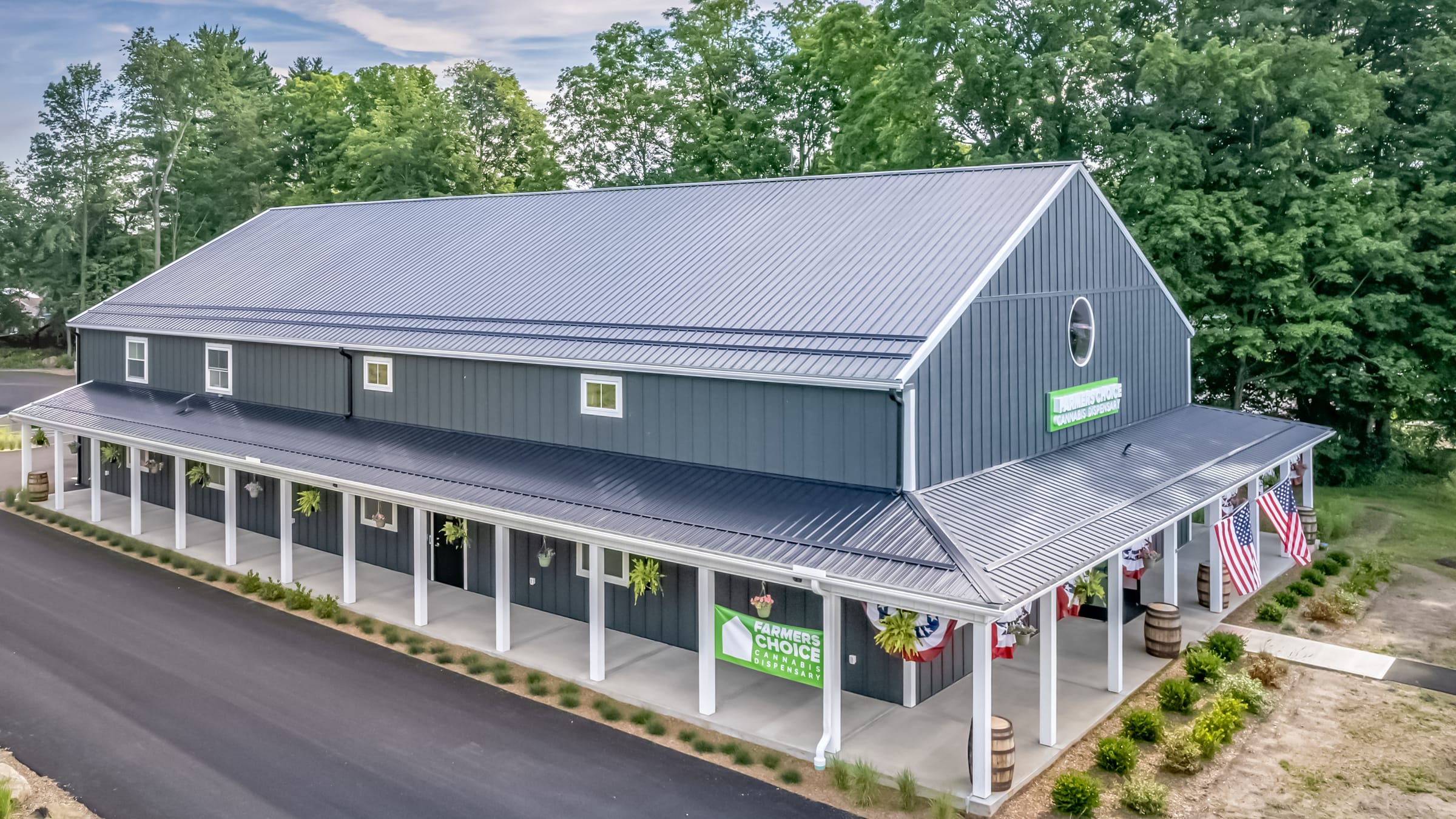 The Farmers Choice New Paltz barn at 1 Old Route 299, gray board-and-batten with a long white-columned porch, bunting and flags along the front