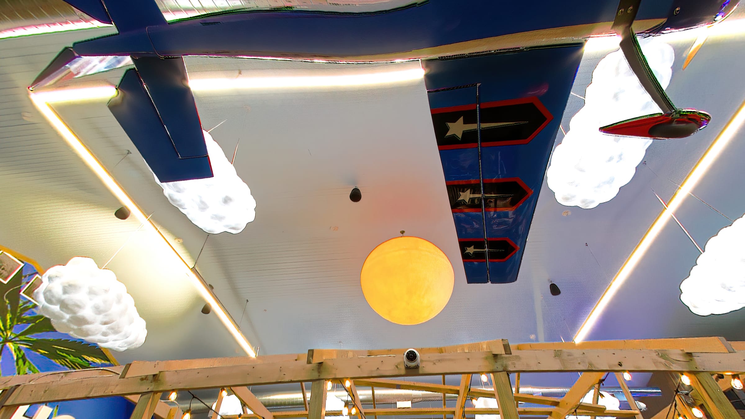 A glowing sun lamp, cloud lamps and a painted plane on the ceiling of the Farmers Choice barn in New Paltz
