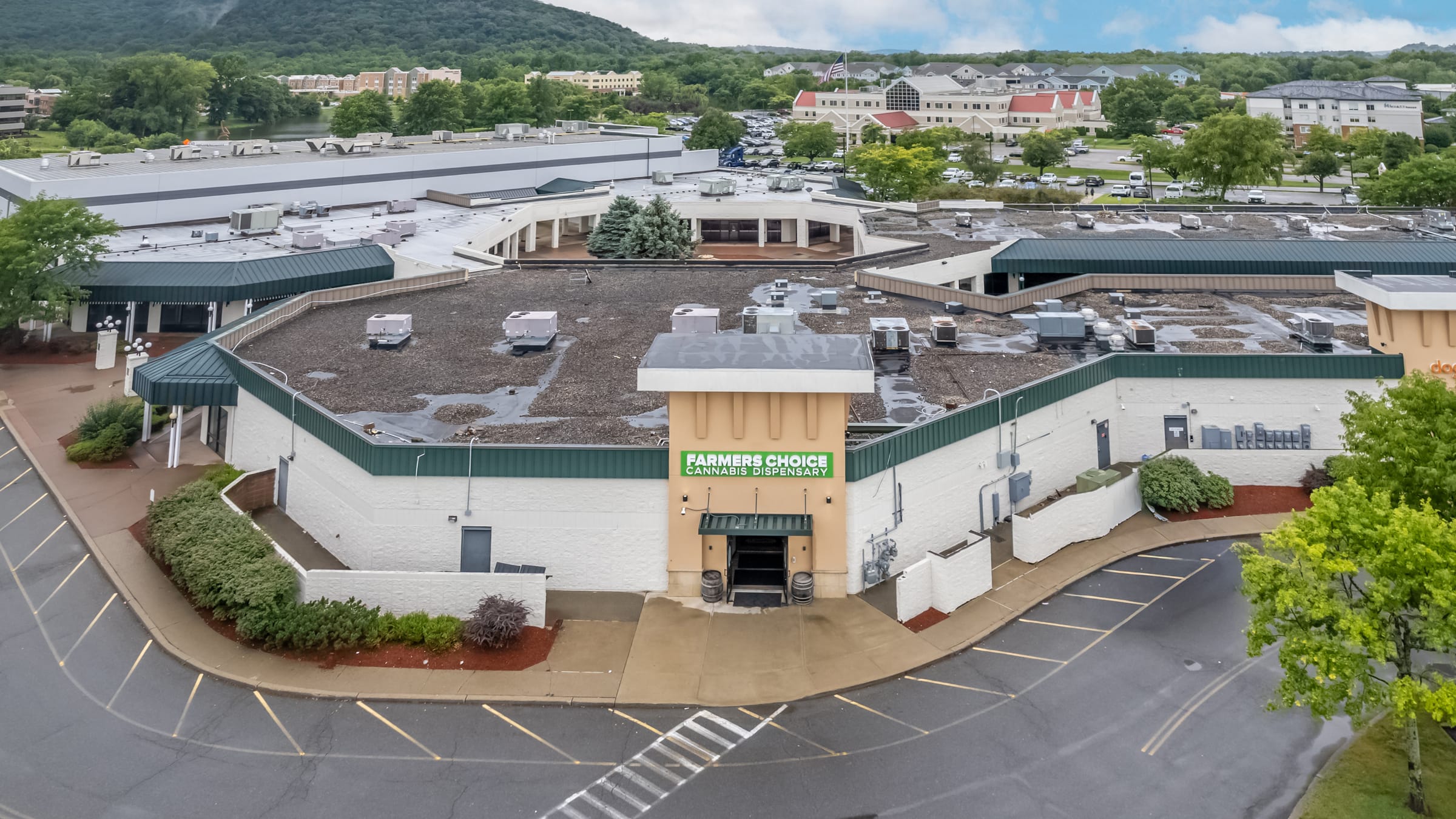 The Farmers Choice Fishkill dispensary at 18 Westage Drive from above, the entrance and parking lot in front and the Hudson Highlands behind