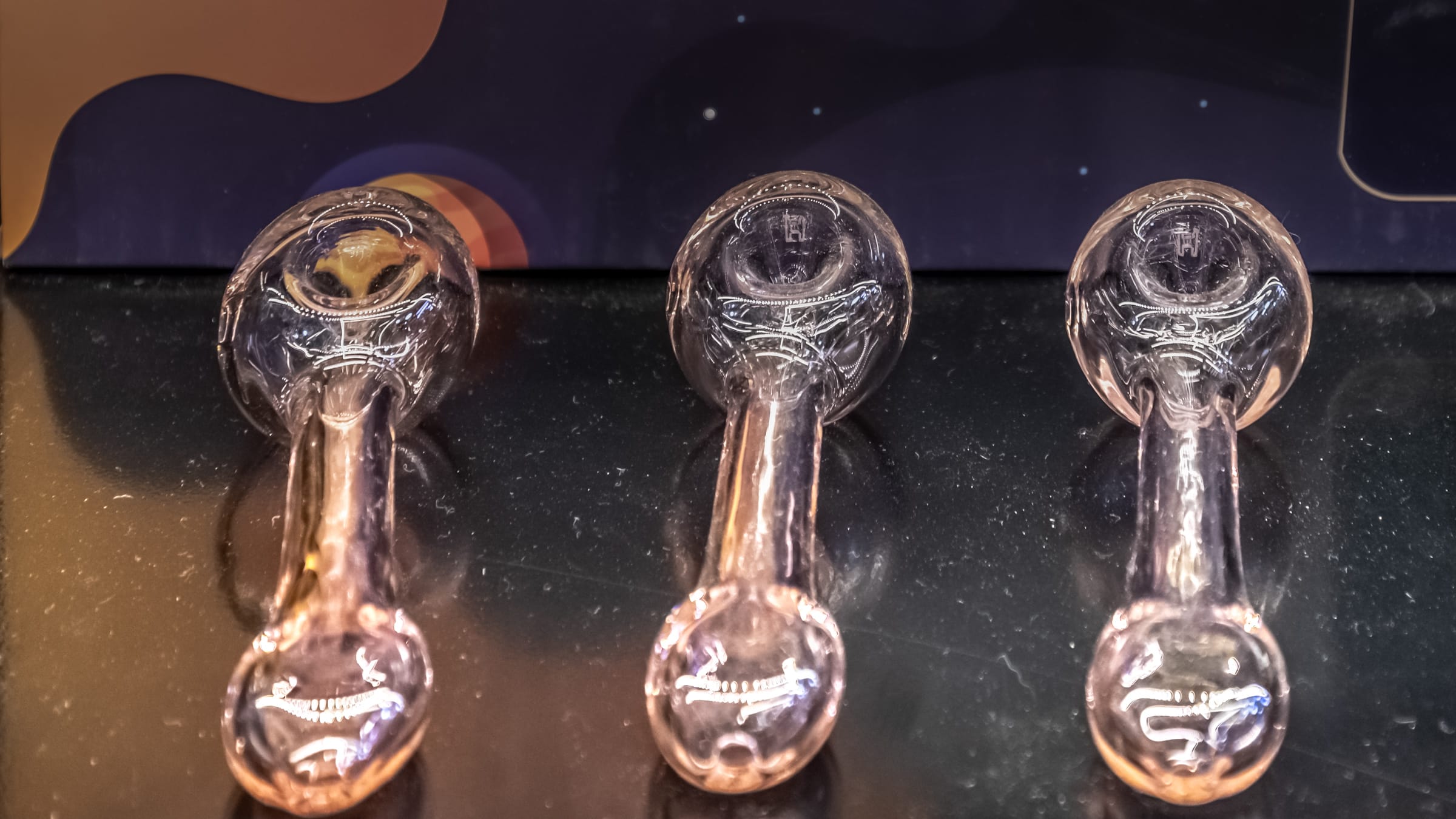 Four glass hand pipes lined up on a black counter at Farmers Choice New Paltz, three clear and one black