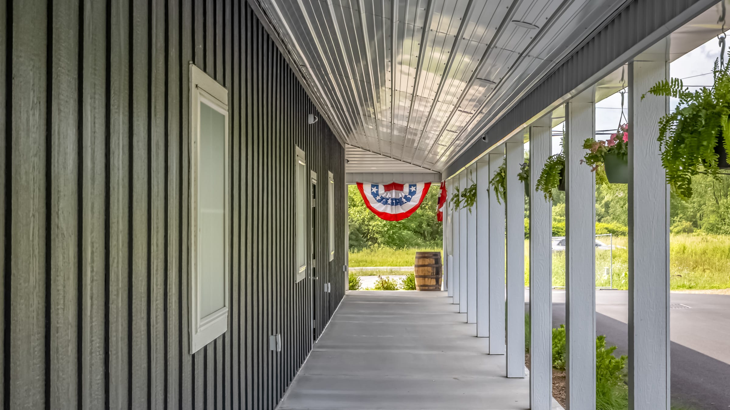 Looking down the covered porch of the Farmers Choice New Paltz barn, red white and blue bunting and a wooden barrel at the far end